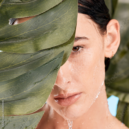 Woman, skincare and jungle leaves by face with water drop, moisturizer and wellness with mystery. Plants, natural cosmetic and water on model skin for health, organic cleaning and facial aesthetic