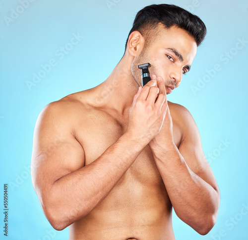 Face, skincare and man with razor shaving in studio isolated on a blue background. Hygiene, grooming and beard shave morning routine of male model from Brazil for wellness, health and smooth skin.