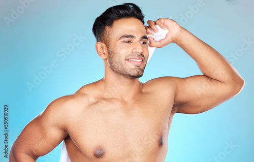 Man, towel and dry after shower, cleaning and wash with clean body, hygiene and bathroom in blue studio background. Skincare, wellness and model with happy smile for beauty,morning and cosmetic