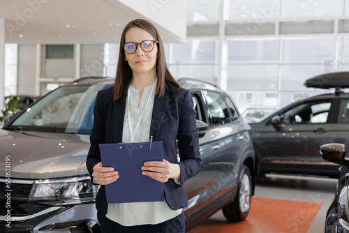 woman sells a car at a car dealership and hands over the keys to the buyer. nice woman car sales manager. a successful and happy woman with a tablet in her hands is the head of a car dealership