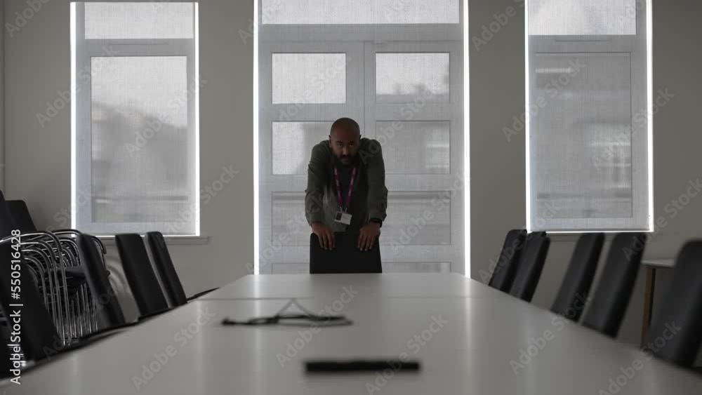 Nervous asian manager alone in empty meeting room waiting for colleagues Nervous asian manager alone in empty meeting room waiting for colleagues