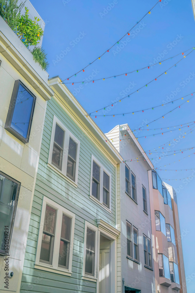 Houses with outdoor string lights against blue sky background on a sunny day. Houses with outdoor string lights against blue sky background on a sunny day.