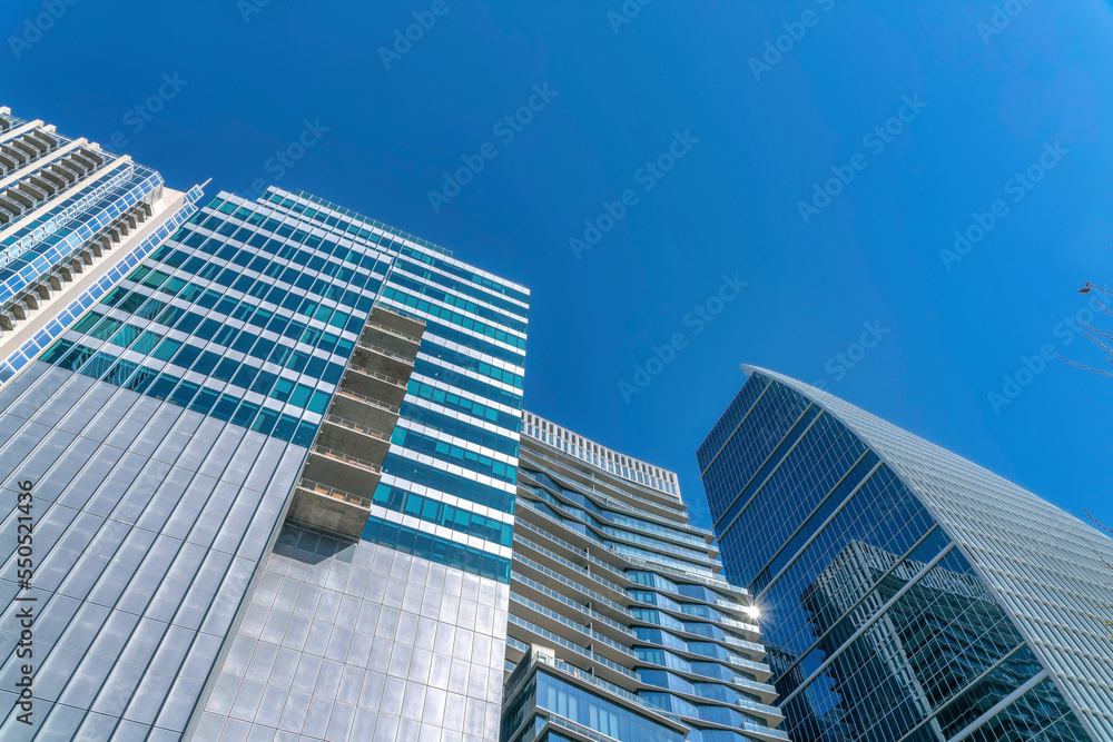 Looking up at modern glass buildings with windows that reflects the city views Looking up at modern glass buildings with windows that reflects the city views
