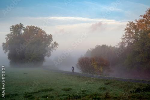 Ein einsamer Radfahrer bahnt sich seinen Weg durch den Morgennebel an einem Flu  