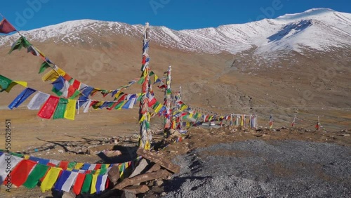Colorful Buddhist Bhutanese Tibetan prayer flag on the side of Kunzum Pass in Spiti Valley, Himachal Pradesh, India. Prayer flags in background of snow covered mountain of Spiti Valley photo