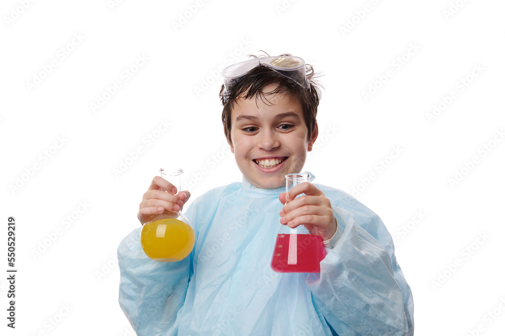 Amazed teenage schoolboy in lab coat, pours solution from beaker into flask, observes the going on chemical reaction with excited and surprised look on his face. Miracles of chemistry. Back to school Amazed teenage schoolboy in lab coat, pours solution from beaker into flask, observes the going on chemical reaction with excited and surprised look on his face. Miracles of chemistry. Back to school