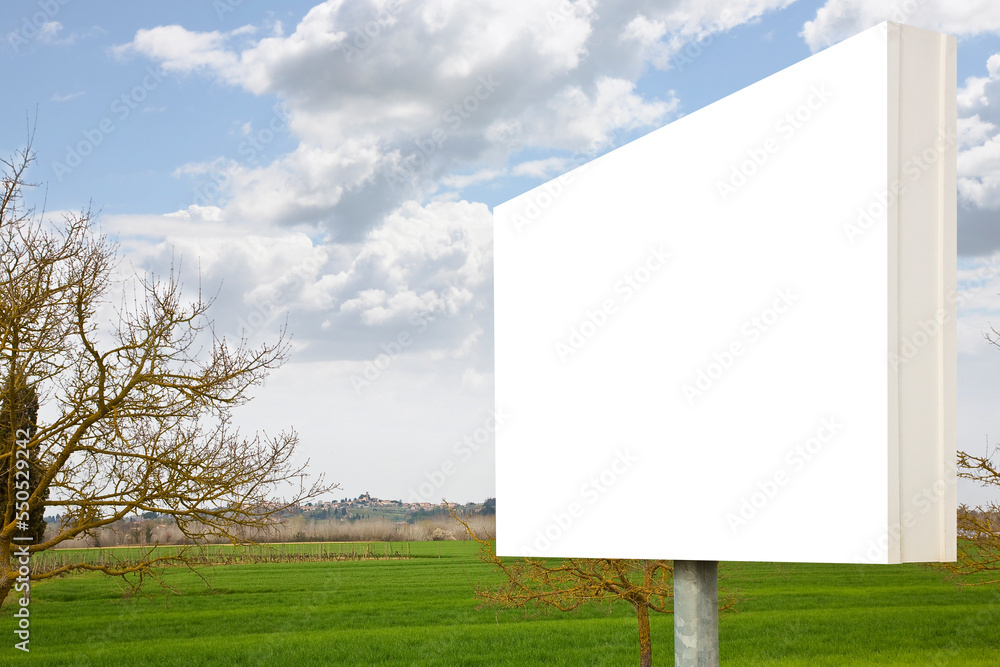 Blank advertising signboard in a green field with trees on background in a Tuscany landscape (Italy) - concept with copy space for text inserting Blank advertising signboard in a green field with trees on background in a Tuscany landscape (Italy) - concept with copy space for text inserting