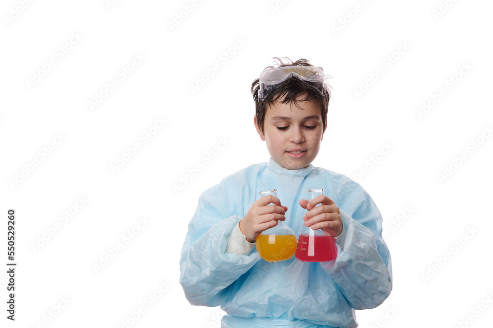 Isolated portrait on white background of a teenager schoolboy in lab coat, doing chemical experiment, adding reagents to solutions in laboratory glassware. Chemistry Science Biology. Free ad space Isolated portrait on white background of a teenager schoolboy in lab coat, doing chemical experiment, adding reagents to solutions in laboratory glassware. Chemistry Science Biology. Free ad space