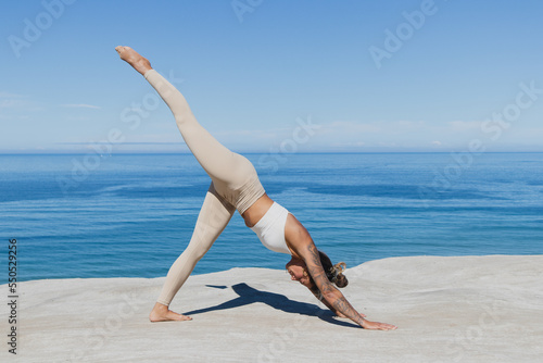 Single leg downward facing dog yoga on the beach