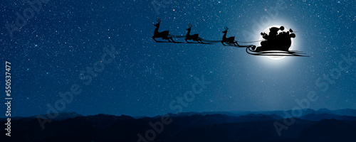 Fotografie, Tablou Santa Claus flies on Christmas Eve in the night sky with snow