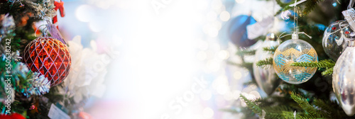Web banner of winter holidays. Close up of colorful toys decorative balls on christmas trees branches. Blurred lighting garlands in background. Copy space. Concept of New Year and xmas celebration