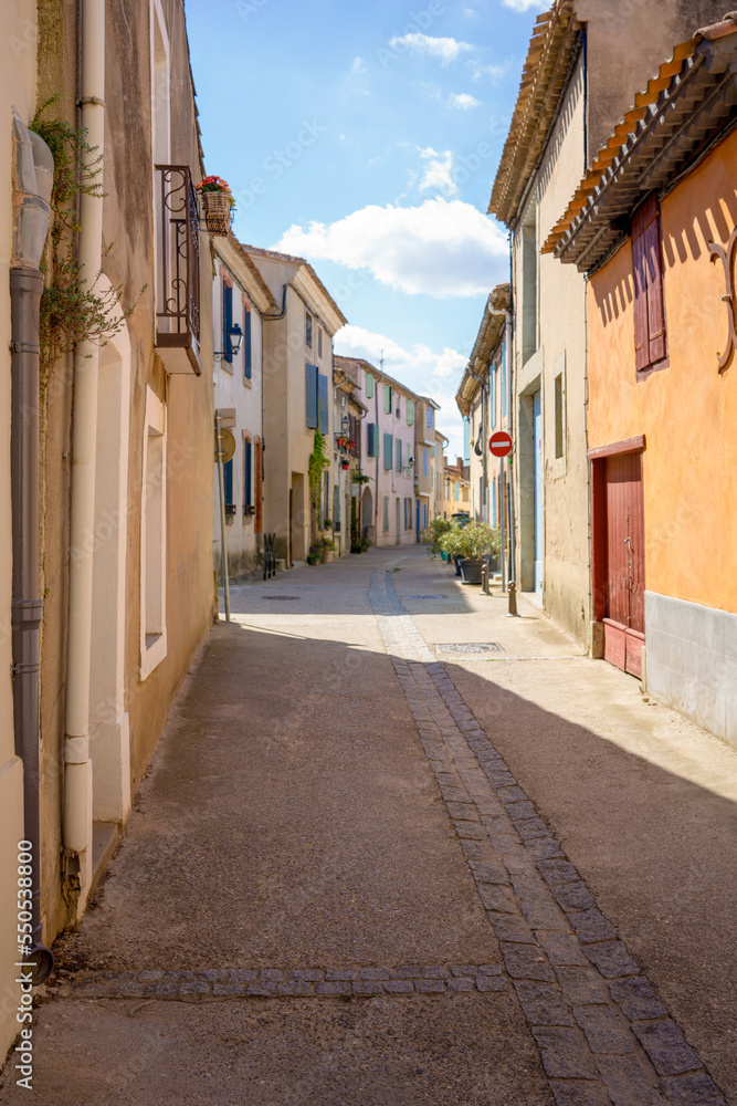Quiet side street in a small French village. Mediterranean houses by day and blue sky.
