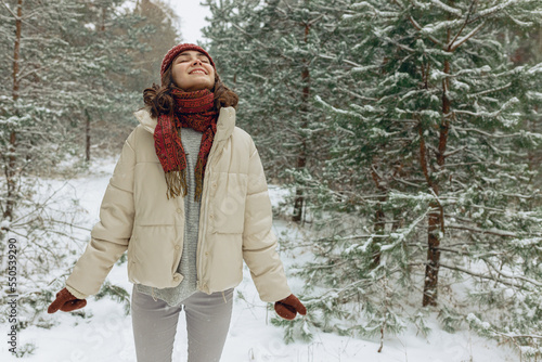 Canvas Print Delighted woman in outerwear enjoying snowy weather in winter forest