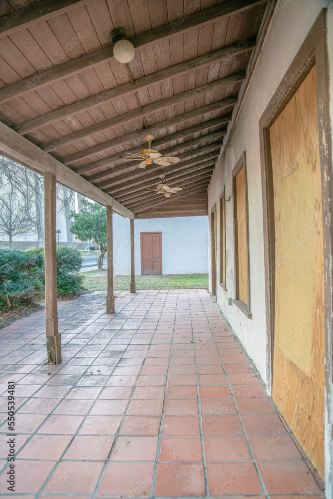 San Antonio, Texas- Red tiles flooring of a porch of an abandoned building with wooden pillars