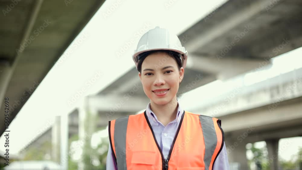 Confident woman Engineer or architect looking camera with white safety helmet in construction site. Supervisor Engineer female working at construction project. Civil engineering concept. Confident woman Engineer or architect looking camera with white safety helmet in construction site. Supervisor Engineer female working at construction project. Civil engineering concept.