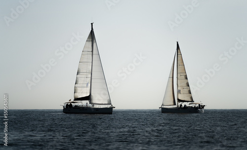 Two sailing ships crossing in the ocean against white sky