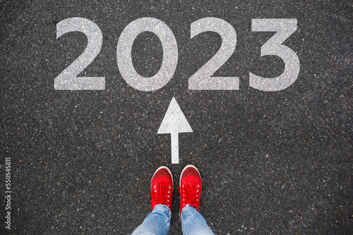 Red sneakers on the asphalt road with passing 2021 to 2022. Concept for success in the future goal and passing time. Happy new year concept