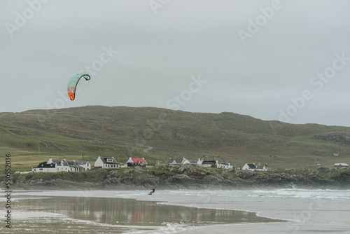 The Isle of Tiree is next to a sea with a Kitesurfer next to it on a cloudy day