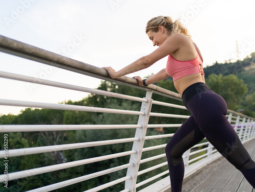 horizontal photo of Young woman doing stretching in city, urban environment, sports clothes