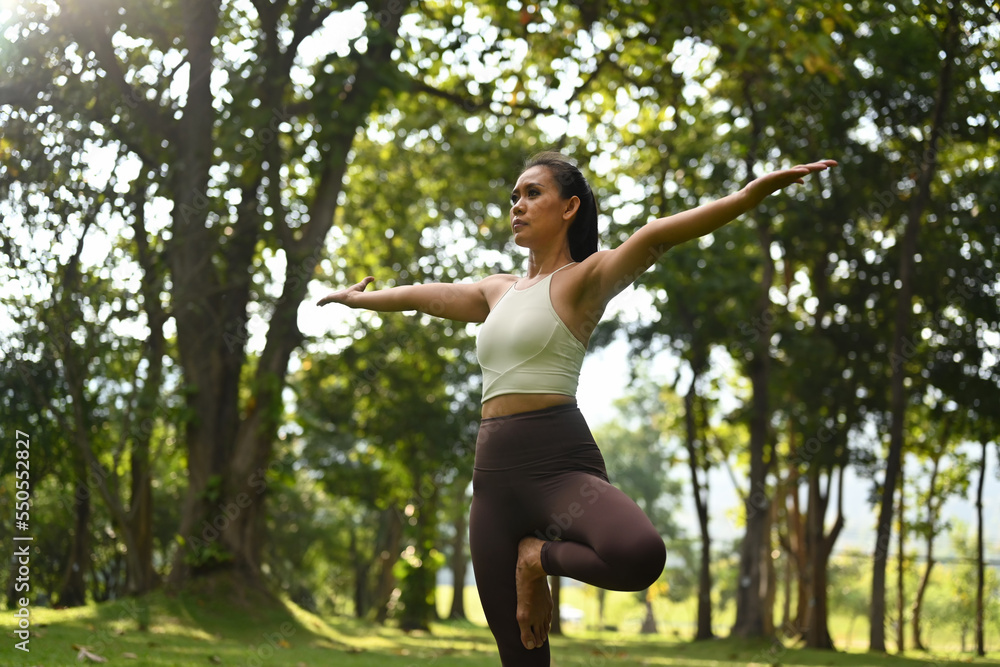Positive millennial women in sportswear practicing yoga lesson with nature environment in background Positive millennial women in sportswear practicing yoga lesson with nature environment in background