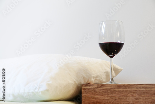 Pillow and wine glass on bedside table. Concept of alcohol drinking abuse and sleeping problem
