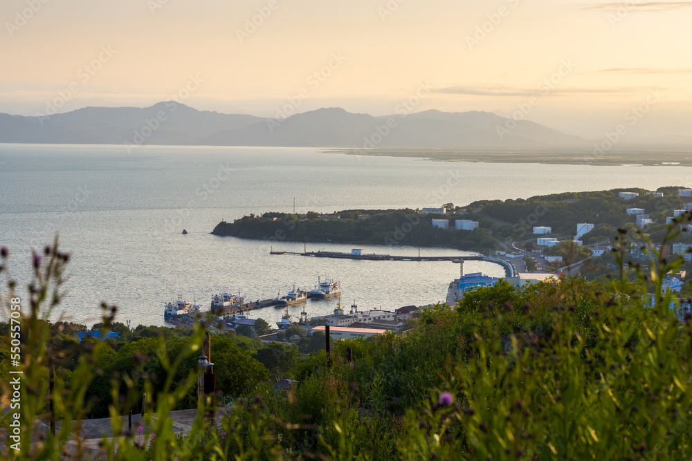 Beautiful evening view of the bay. Ships are moored near the pier. Large tanks with fuel on the shore. Coast of Avacha Bay, Petropavlovsk-Kamchatsky, Kamchatka Territory, Far East of Russia.