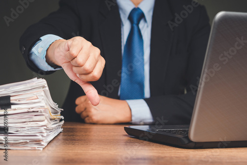 Close-up of businessman's hand showing a thumbs down for dislike service photo