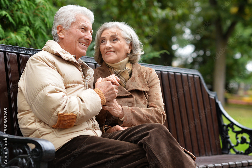 Beautiful elderly couple sitting together on a bench in autumn Beautiful elderly couple sitting together on a bench in autumn