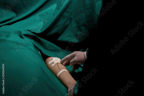 A nurse is preparing a patient before surgery being given saline solution. © ND STOCK