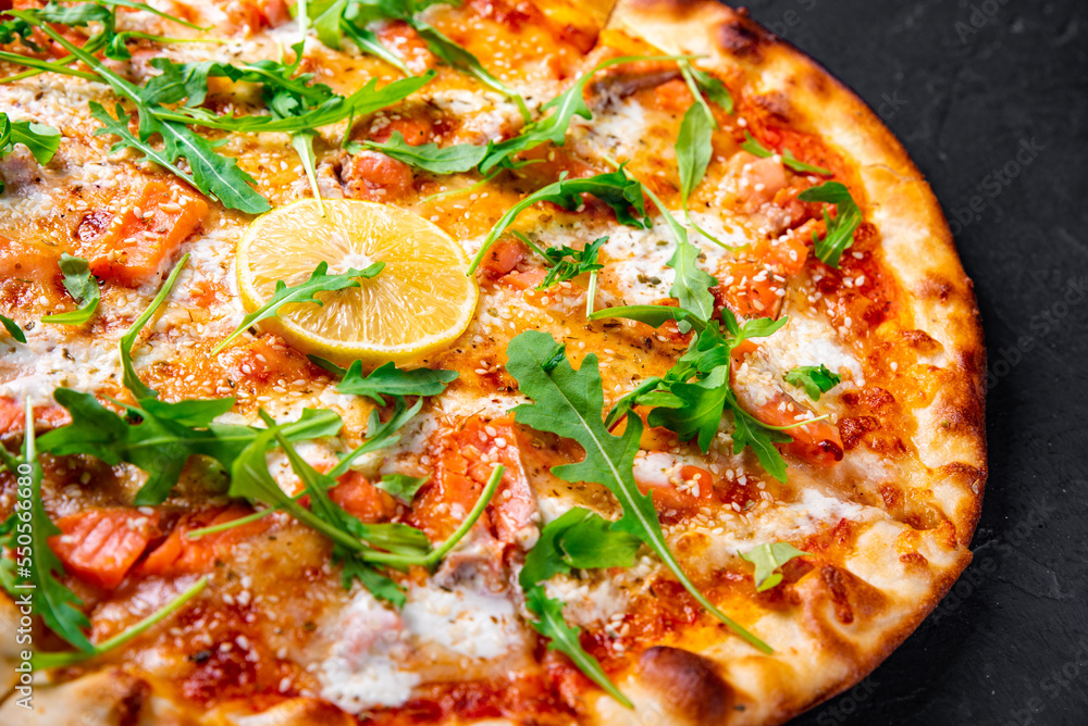 Pizza with Mozzarella cheese, salmon fish, tomato sauce, arugula, lemon