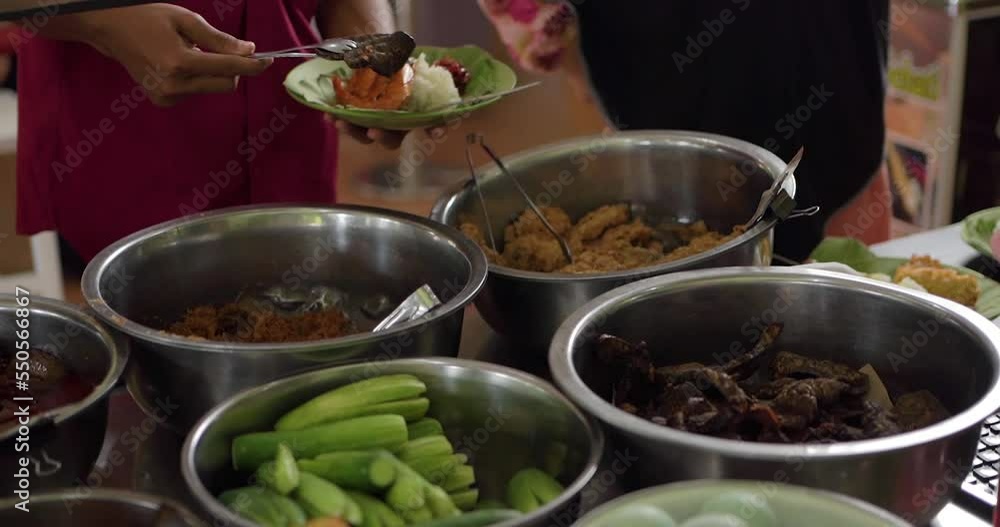 Customers take fried beef lung on the Nasi Jamblang menu. Traditional rice dish from Cirebon, West Java. Steamed rice wrapped in fragrant teak leaf and served with plenty of side dishes. Customers take fried beef lung on the Nasi Jamblang menu. Traditional rice dish from Cirebon, West Java. Steamed rice wrapped in fragrant teak leaf and served with plenty of side dishes.