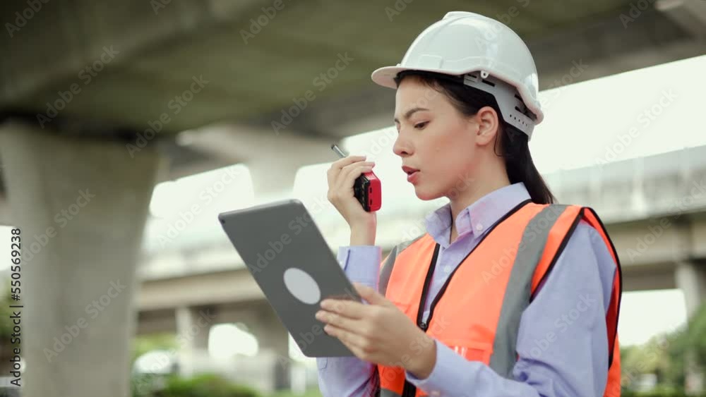 Confident woman Engineer or architect looking and Using tablet for checking and maintenance to inspection in construction site. Using walkie talkie control highway road. Civil engineering concept. Confident woman Engineer or architect looking and Using tablet for checking and maintenance to inspection in construction site. Using walkie talkie control highway road. Civil engineering concept.