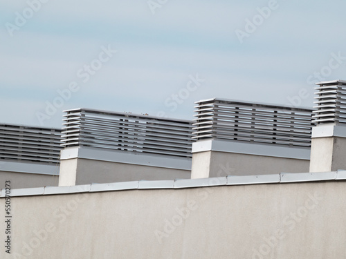 House outdoor roof ventilation units on sunny day on sky background. Air conditioner system set on building roof. Architecture elements close-up