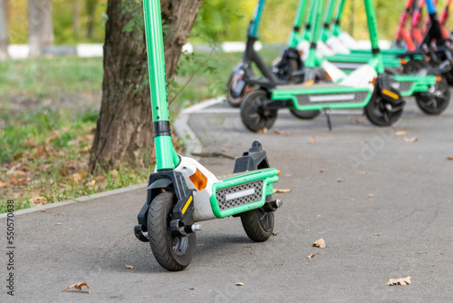 Electric Scooters parking in autumn city streets. Public e-scooter with blurred background, green popular transport