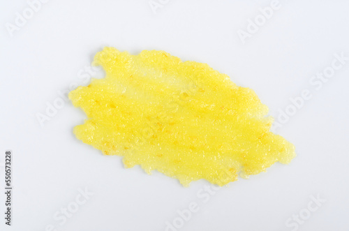 Yellow lemon face or body exfoliating scrub texture. Beauty mask smear on white background. Cosmetic product swatch close-up.