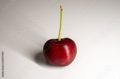 one red cherry standing in a white background