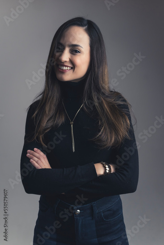 A medium shot of young brunette smiling woman standing with arms croseed. High quality photo