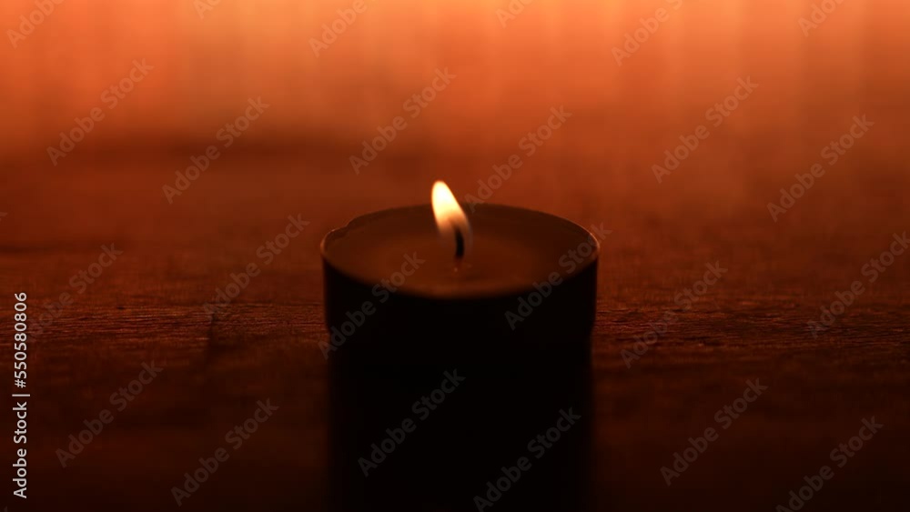 The flame of one lighted candle moves with the wind at a slow pace. A candle on a yellow background. Wax candle