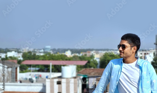 Asian smiling young man wearing black sunglasses looking sideways