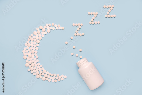 Medical supplement in the evening. Concept Insomnia, sleep problems. Pills in shape of the moon and white bottle on blue background