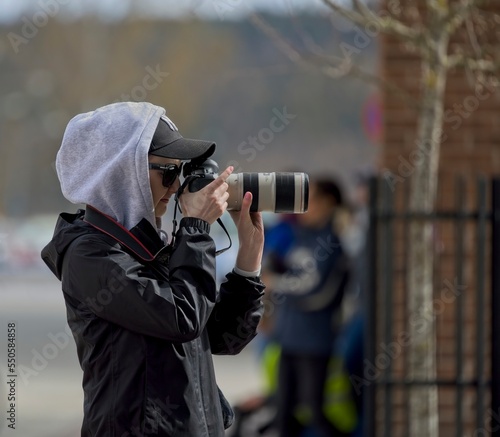 Female photographer working for a local newspaper with a cap and hood on her head