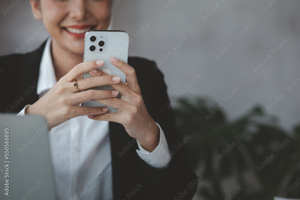 Beautiful Asian woman playing mobile phone in her break from work, she is a marketing manager of a startup company, female leader, supervisor, ceo. Female Leadership Concept. Beautiful Asian woman playing mobile phone in her break from work, she is a marketing manager of a startup company, female leader, supervisor, ceo. Female Leadership Concept.