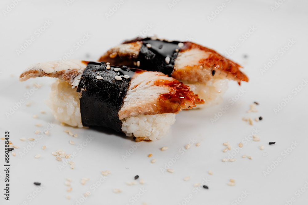 Two portions of sushi with shrimp and eel on a white plate. Two portions of sushi with shrimp and eel on a white plate.