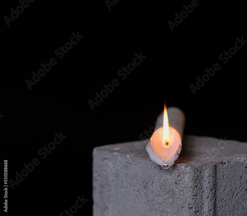 Obraz na plátně Overturned burning paraffin candle on gray cobblestone