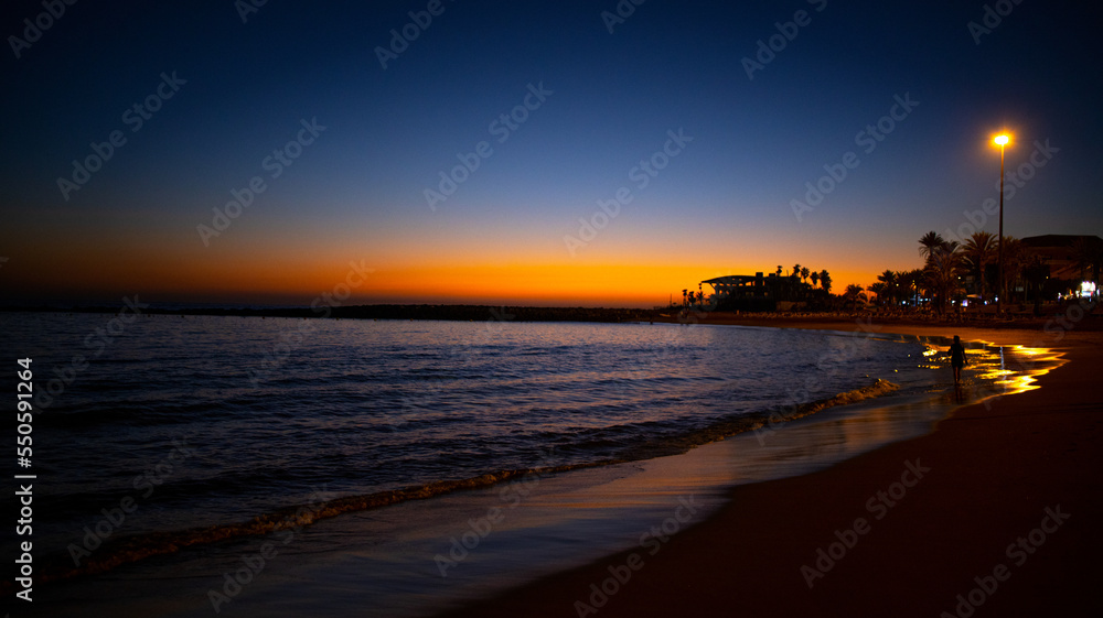 Fototapeta premium A woman walks at sunset on Las Vistas beach, Tenerife