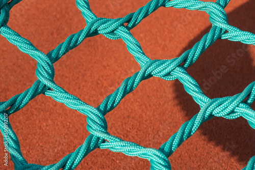 Green rope net closeup against orange background.