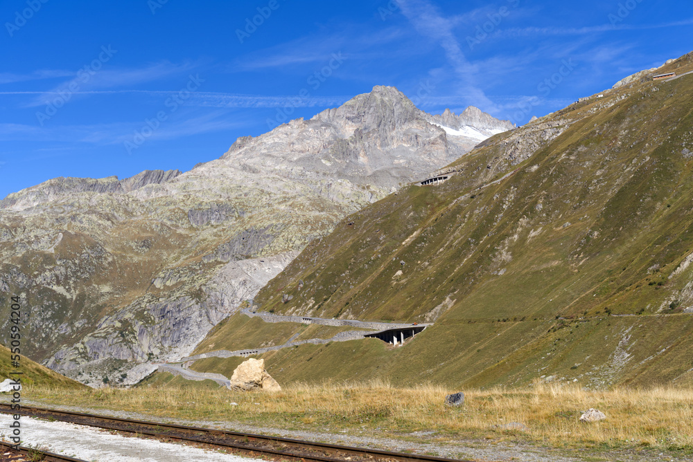 Aerial view of mountain panorama in the Swiss Alps at region of Swiss mountain pass Furkapass with serpentine road on a sunny summer day. Photo taken September 12th, 2022, Furka Pass, Switzerland.