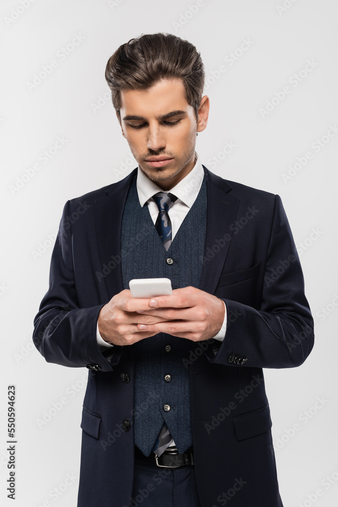 successful businessman in suit messaging on smartphone isolated on grey successful businessman in suit messaging on smartphone isolated on grey