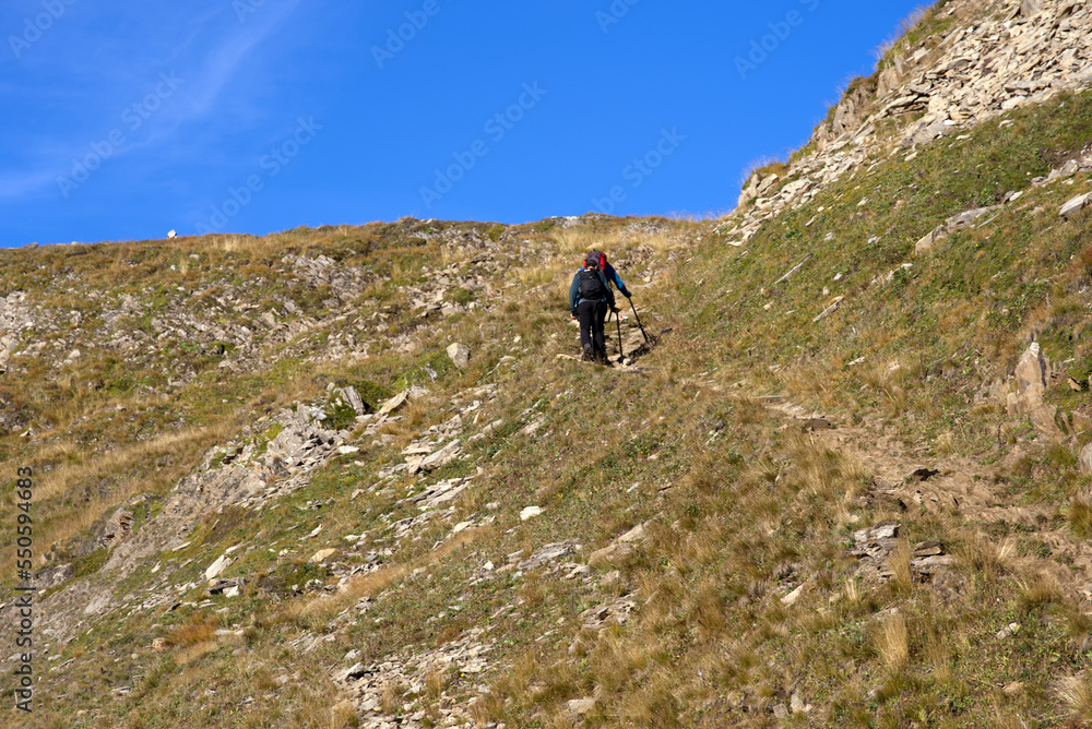 Beautiful scenic landscape with female hiker way up at summit of Swiss mountain pass Furkapass on a sunny late summer day. Photo taken September 12th, 2022, Gletsch, Switzerland.