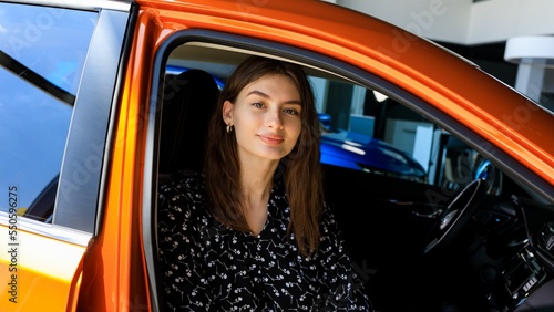 Portrait of a young woman in a car. Buying a new car at a dealership